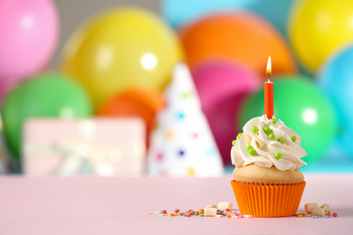 Photo of Birthday cupcake with candle on pink table against blurred background. Space for text