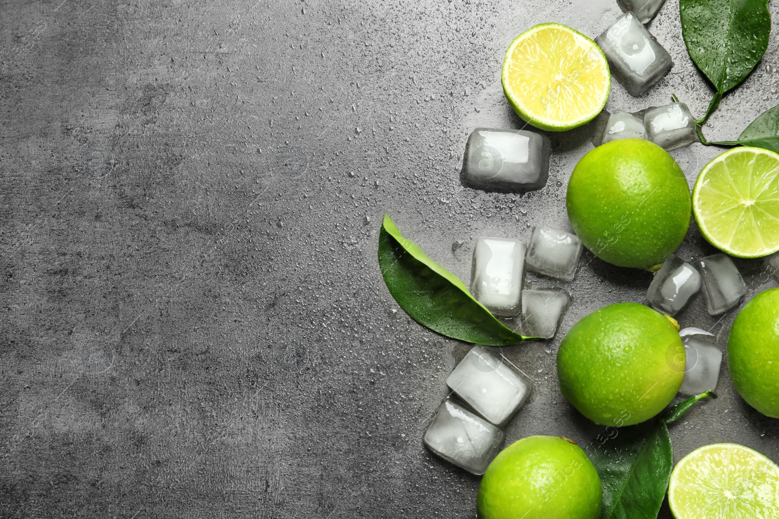 Photo of Composition with fresh ripe limes and ice cubes on gray background, top view