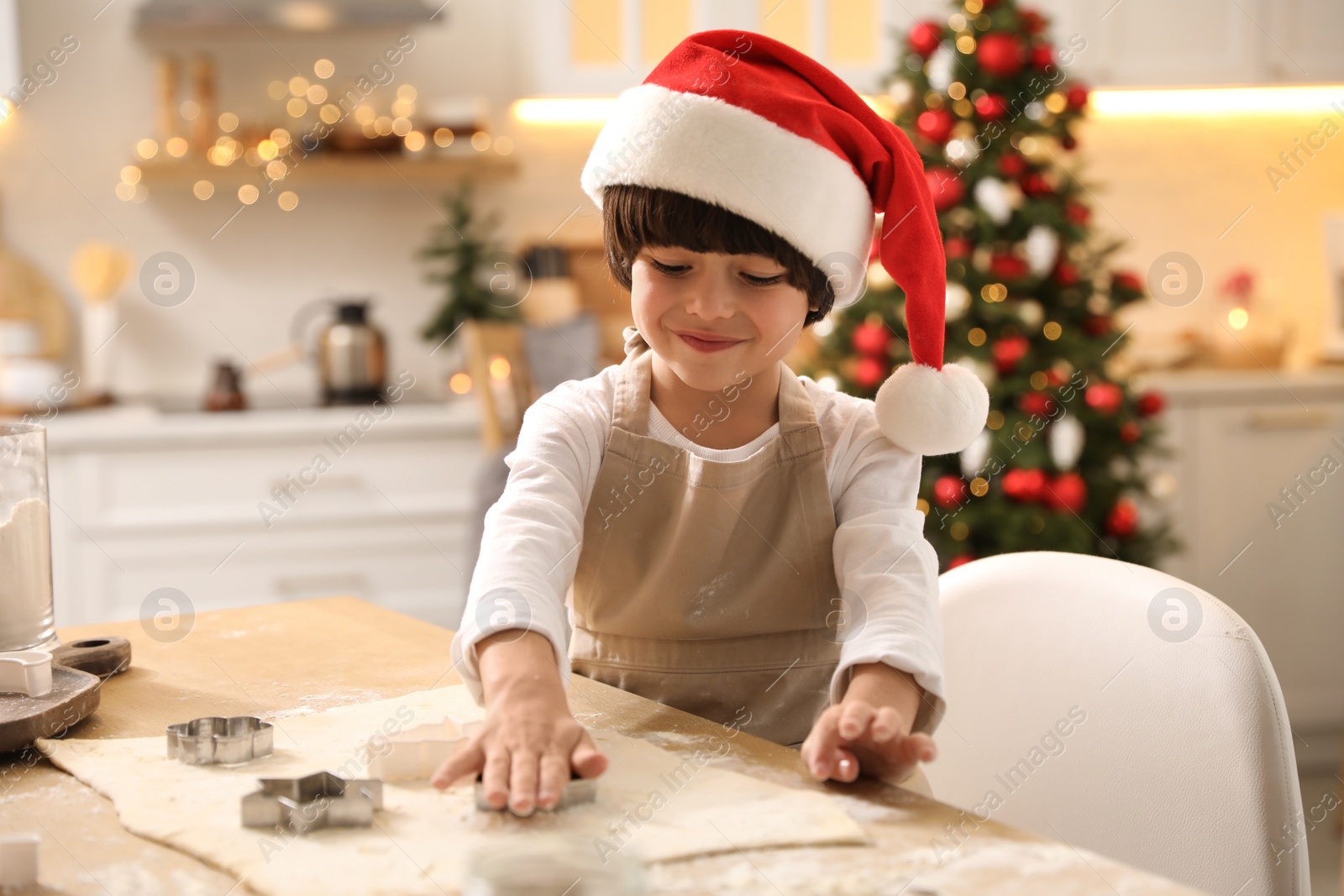 Photo of Cute little boy making Christmas cookies in kitchen