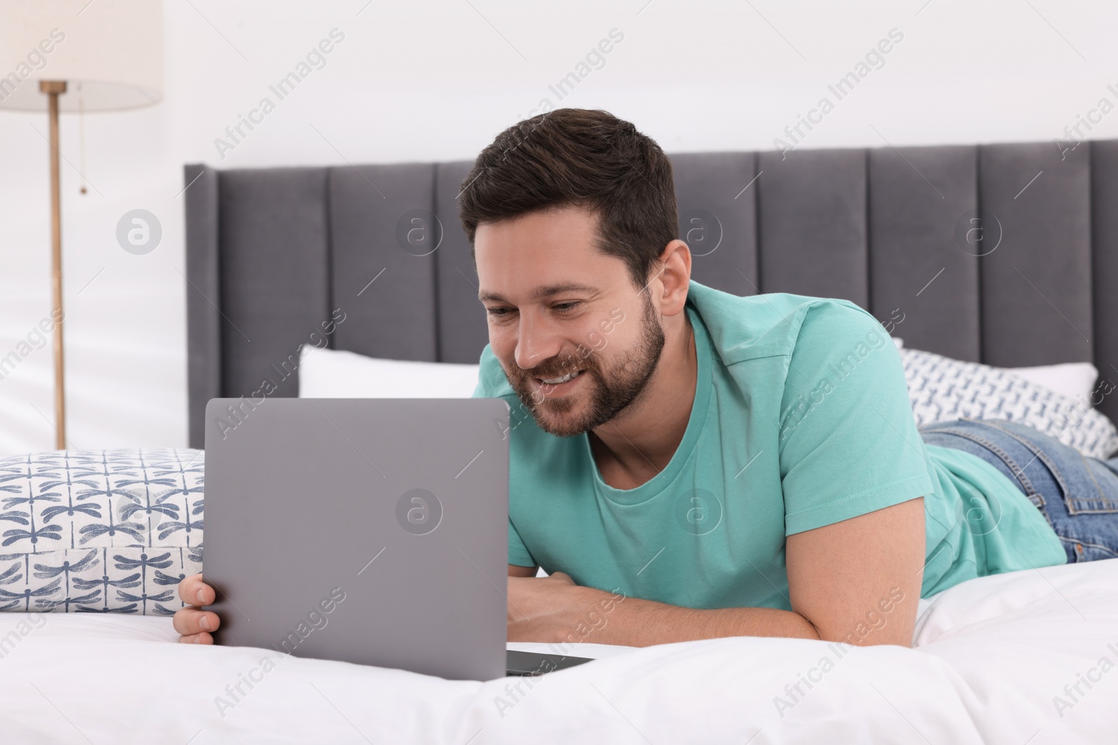 Photo of Happy man having video chat via laptop in bedroom