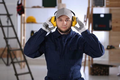 Photo of Worker wearing safety headphones indoors. Hearing protection device