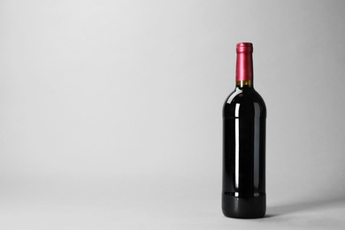 Photo of Bottle of wine on grey background. Space for text