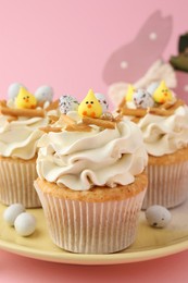 Photo of Tasty Easter cupcakes with vanilla cream on pink background, closeup