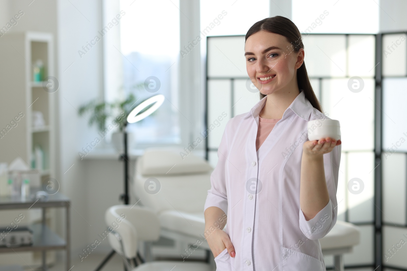 Photo of Cosmetologist with cosmetic product in modern clinic