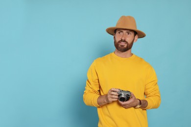 Man with camera on light blue background, space for text. Interesting hobby