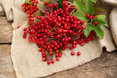 Photo of Branch of viburnum with ripe berries on wooden table, flat lay