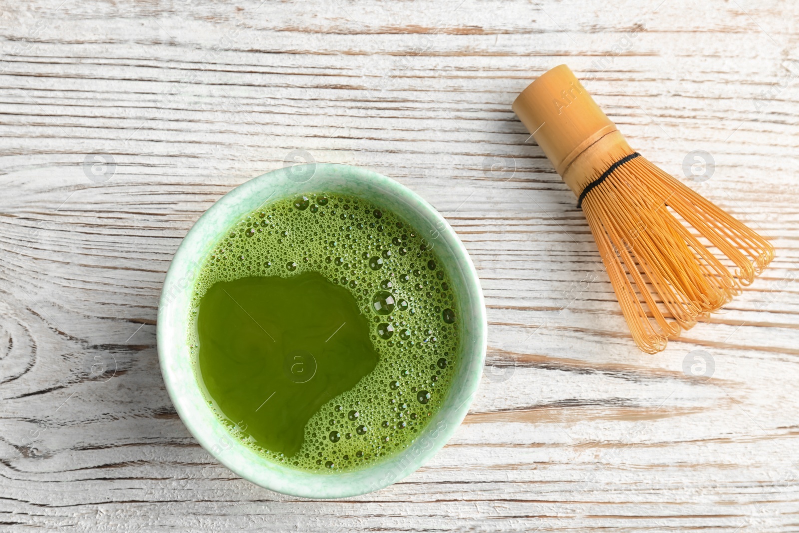 Photo of Chawan with fresh matcha tea and chasen on table, top view