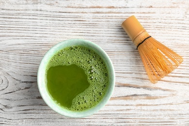 Photo of Chawan with fresh matcha tea and chasen on table, top view