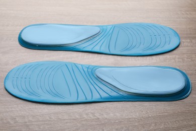 Photo of LIght blue orthopedic insoles on wooden background