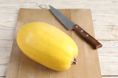 Photo of Ripe spaghetti squash and knife on wooden board