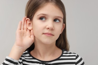 Little girl with hearing problem on grey background