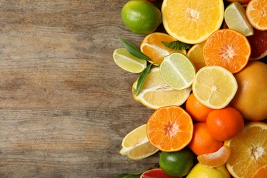 Different citrus fruits on wooden background, top view. Space for text