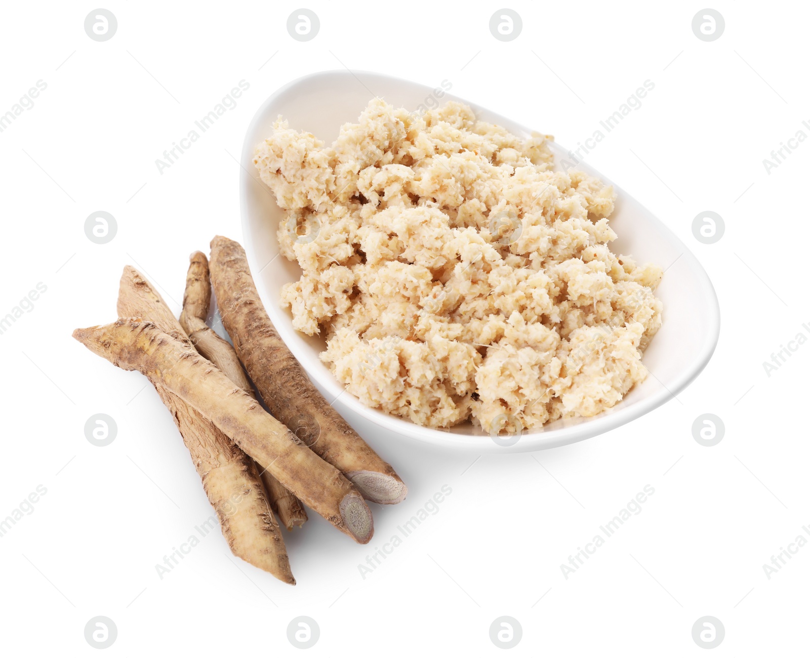 Photo of Bowl of tasty prepared horseradish and roots isolated on white