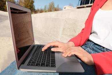 Image of Young woman working on laptop outdoors, closeup