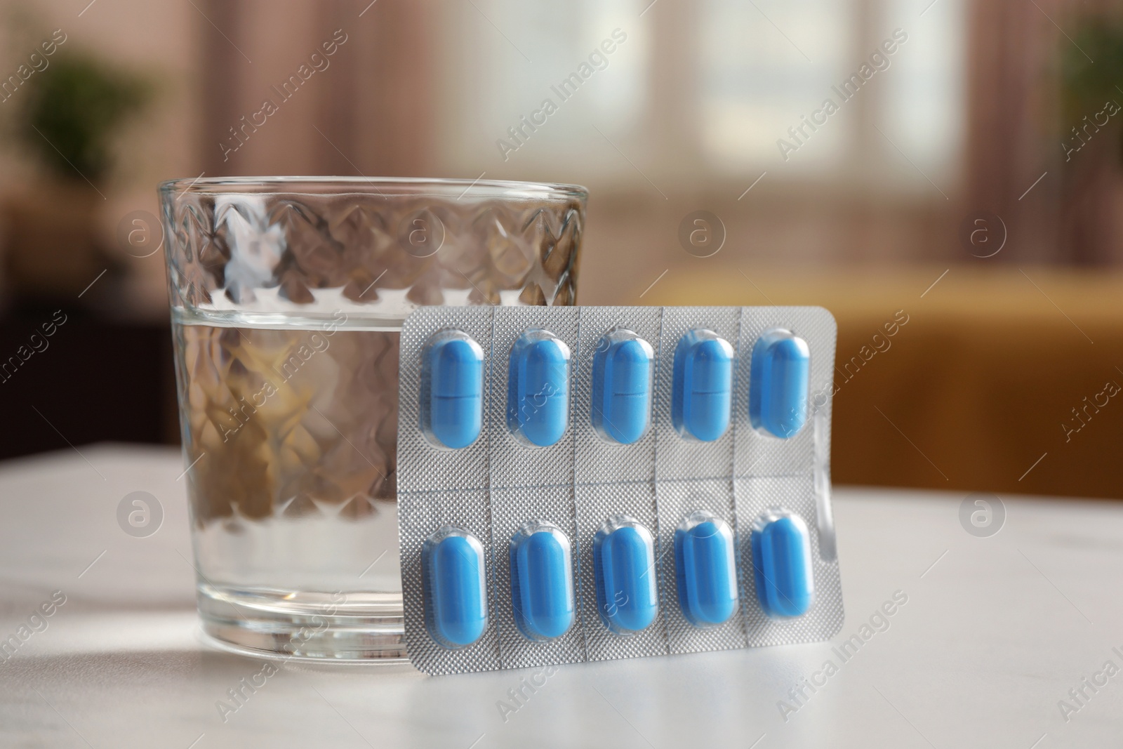 Photo of Glass of water and pills on white table indoors, closeup. Potency problem concept