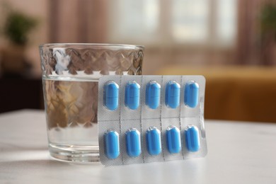 Glass of water and pills on white table indoors, closeup. Potency problem concept