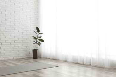 Photo of Unrolled grey yoga mat on floor in room. Space for text