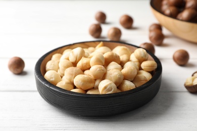 Plate with shelled organic Macadamia nuts on white table