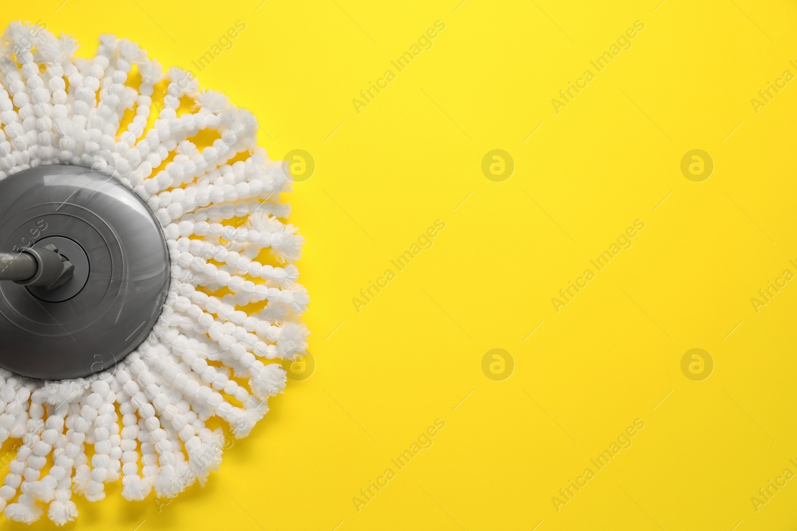 Photo of Mop with metal handle on yellow background, top view. Space for text