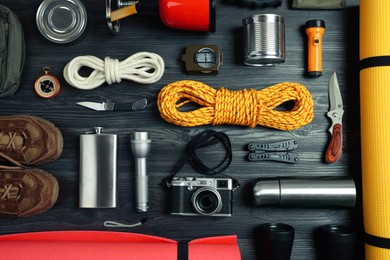 Photo of Flat lay composition with different camping equipment on dark wooden background. Traveler set