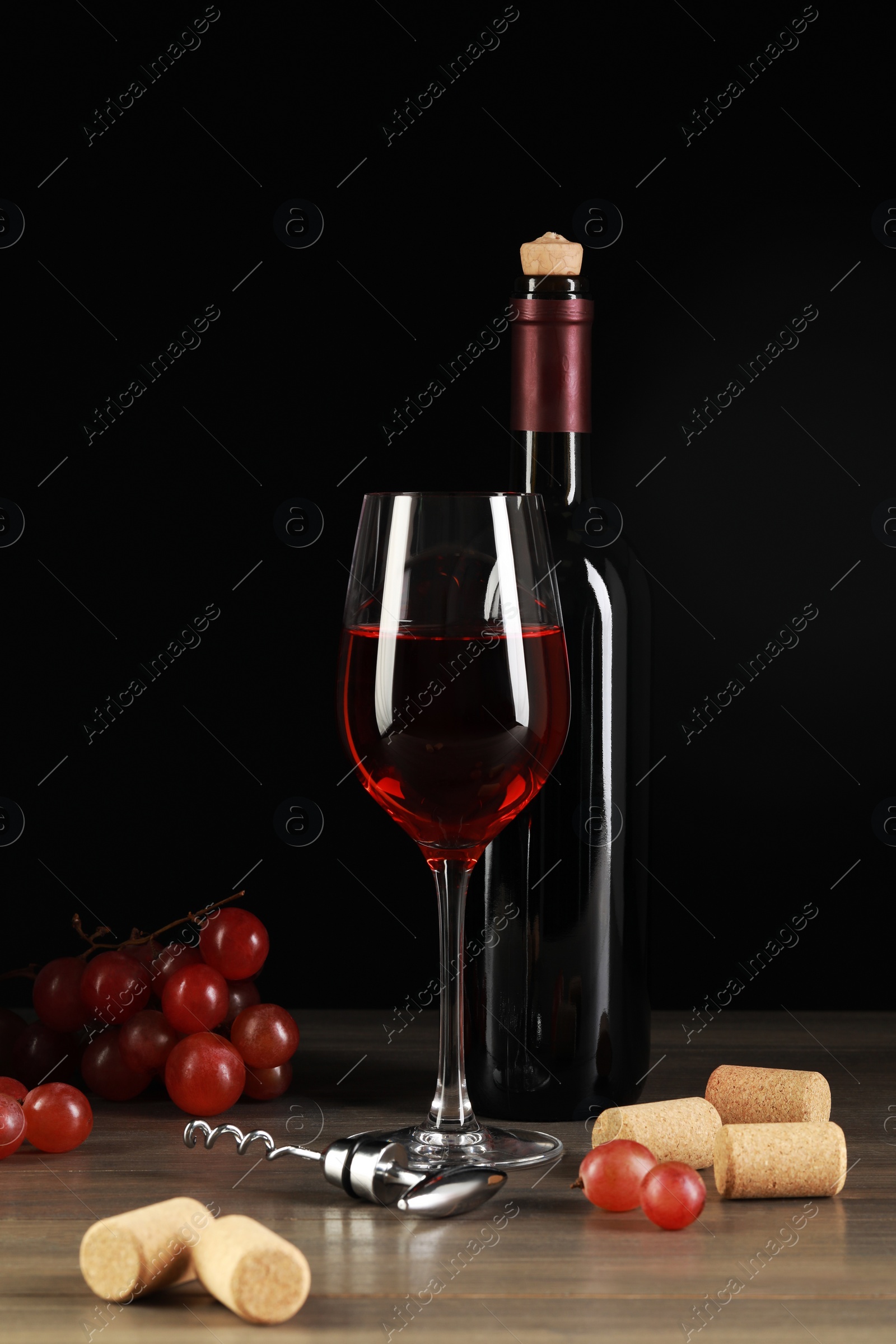 Photo of Wine, corks, grapes and corkscrew on wooden table