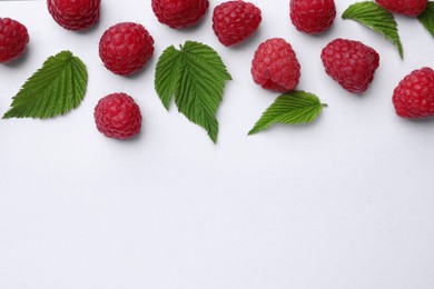 Photo of Tasty ripe raspberries and green leaves on white background, flat lay. Space for text