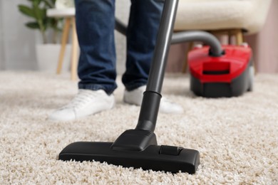 Man cleaning carpet with vacuum cleaner at home, closeup