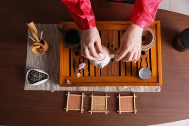 Photo of Master conducting traditional tea ceremony at wooden table, top view