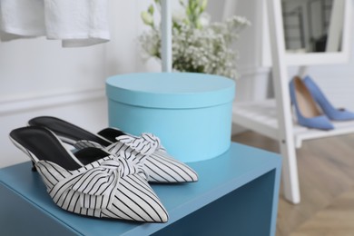 Photo of Elegant women's shoes on light blue shelf in dressing room