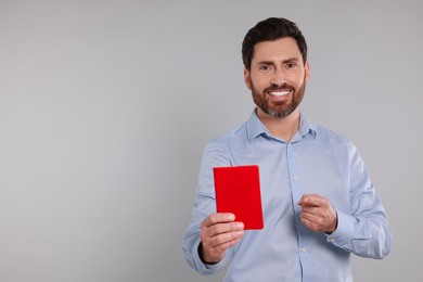 Photo of Immigration. Happy man with passport on gray background, space for text