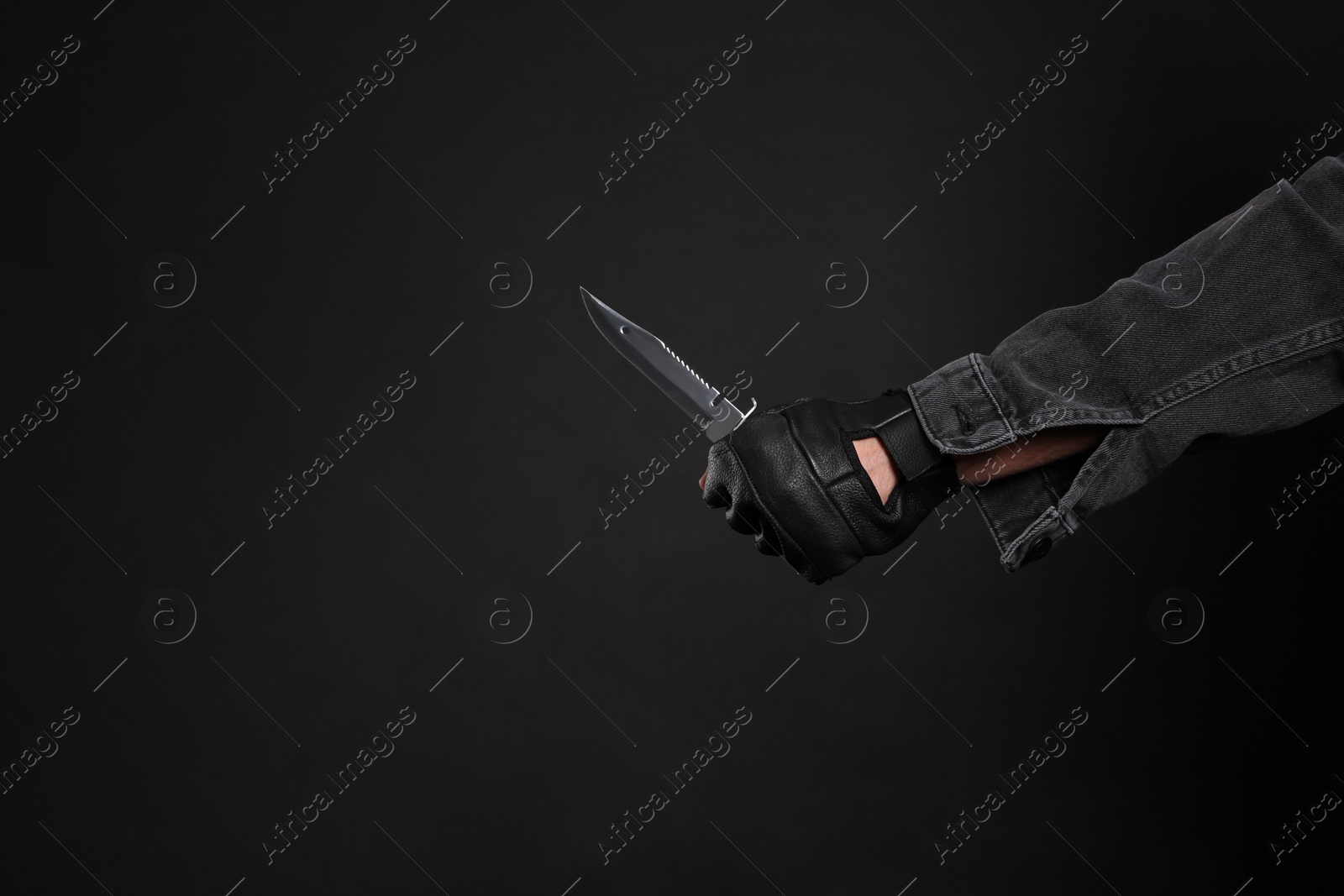 Photo of Man holding knife on black background, closeup with space for text. Dangerous criminal