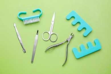 Photo of Set of pedicure tools on light green background, flat lay