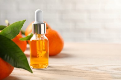 Bottle of tangerine essential oil and fresh fruits on white wooden table, closeup. Space for text