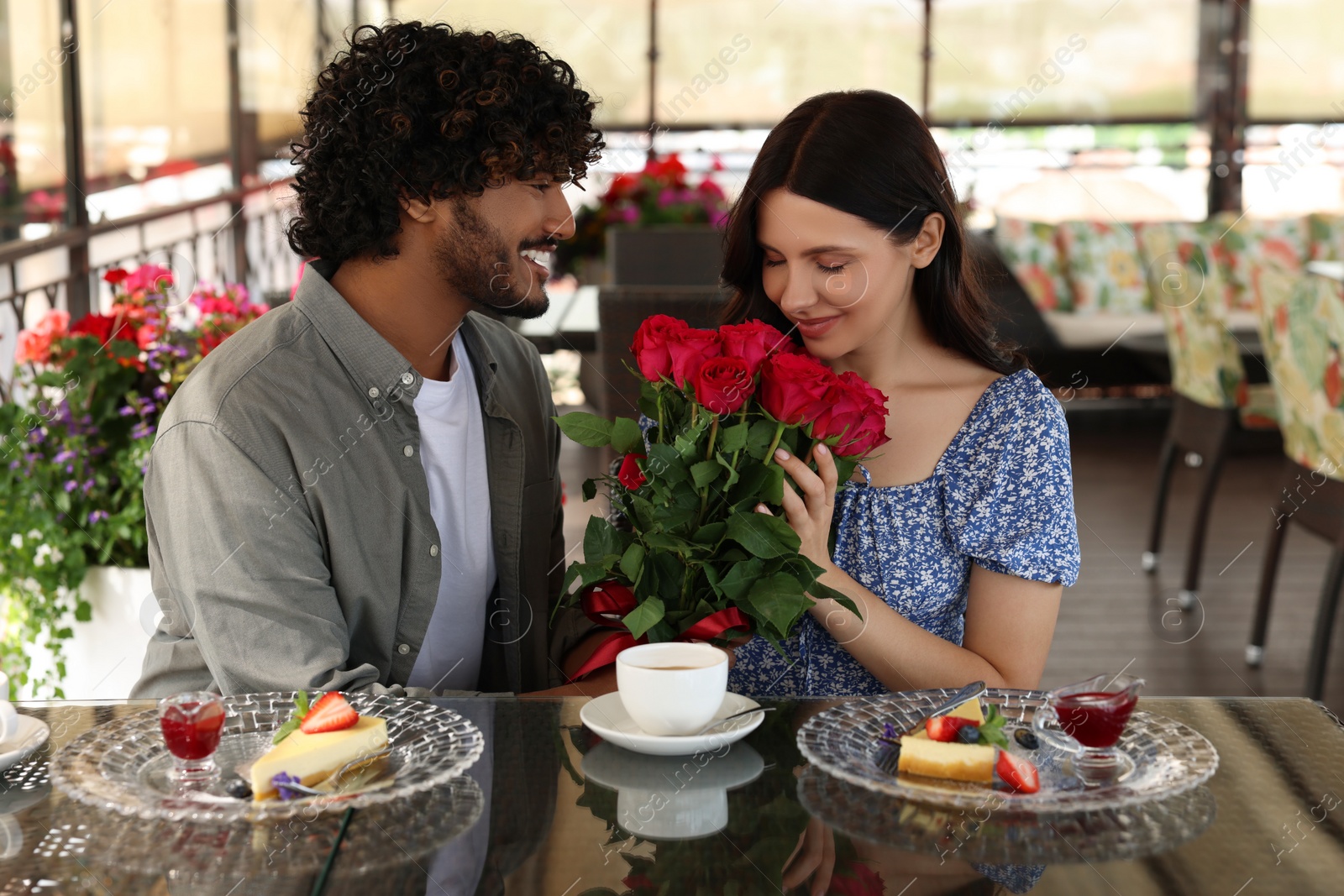 Photo of International dating. Handsome man presenting roses to his girlfriend in restaurant