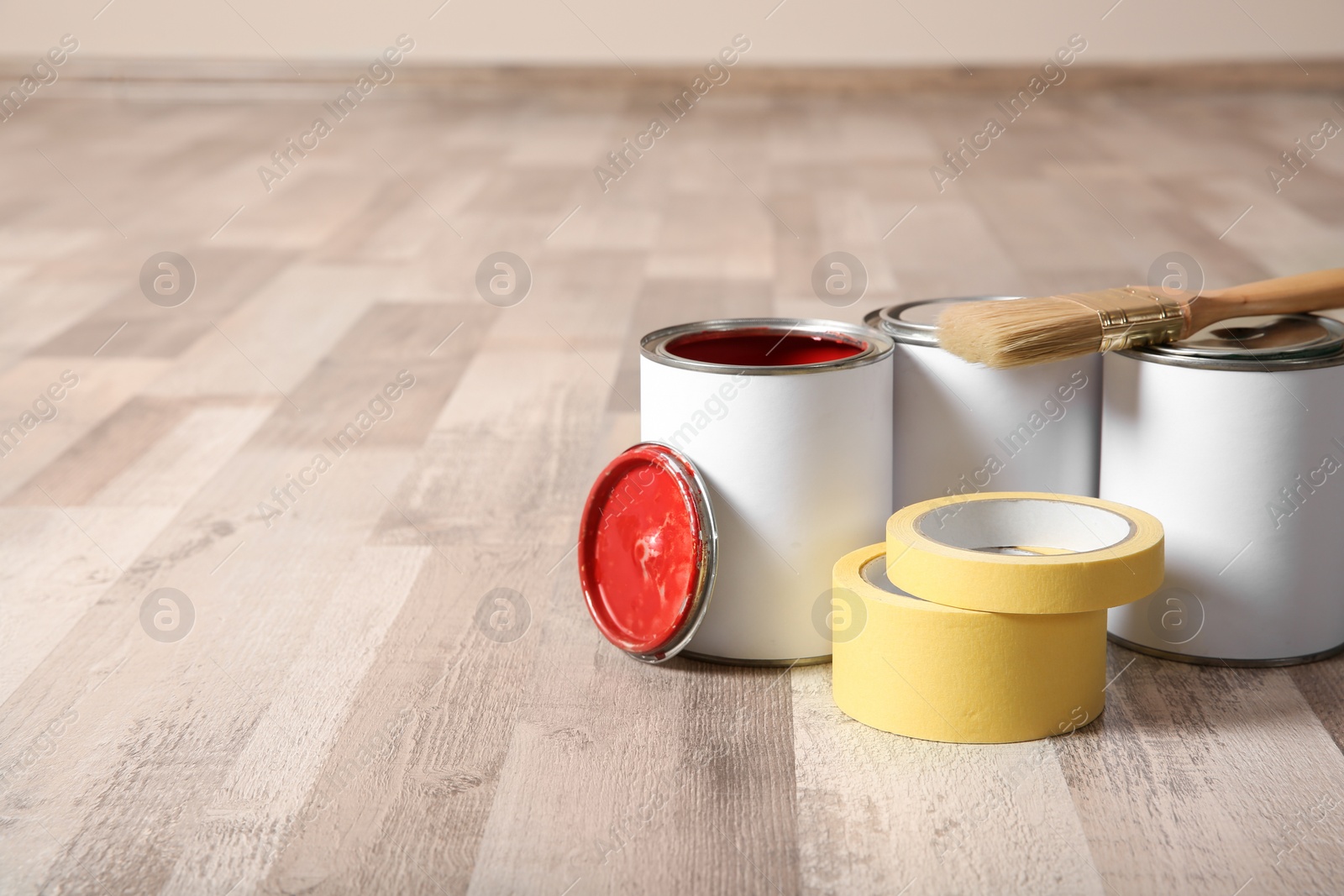 Photo of Cans of paint and decorator tools on wooden floor indoors. Space for text