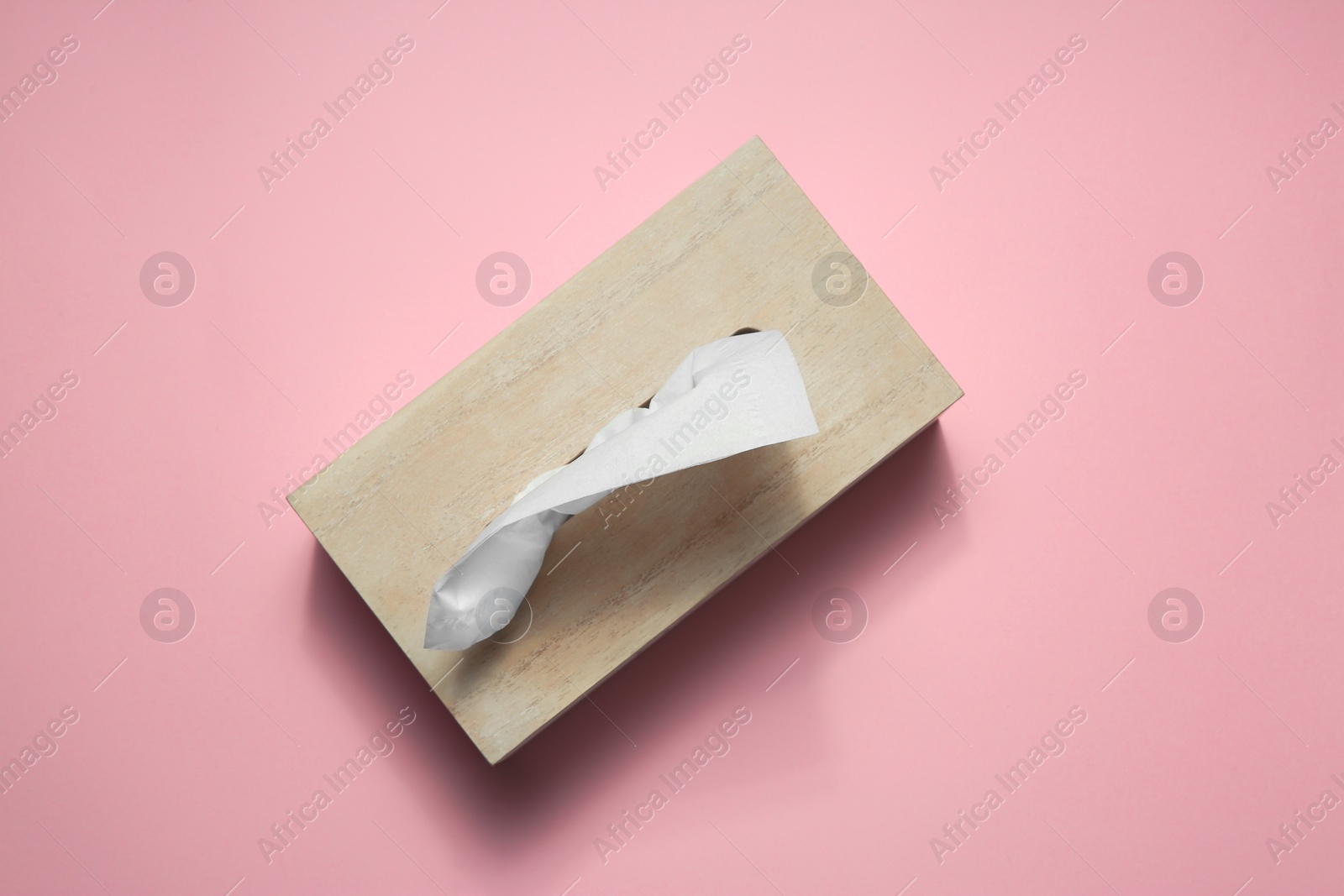 Photo of Wooden holder with paper tissues on pink background, top view