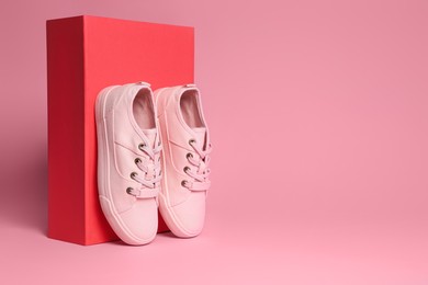 Pair of stylish canvas shoes and box on pink background. Space for text