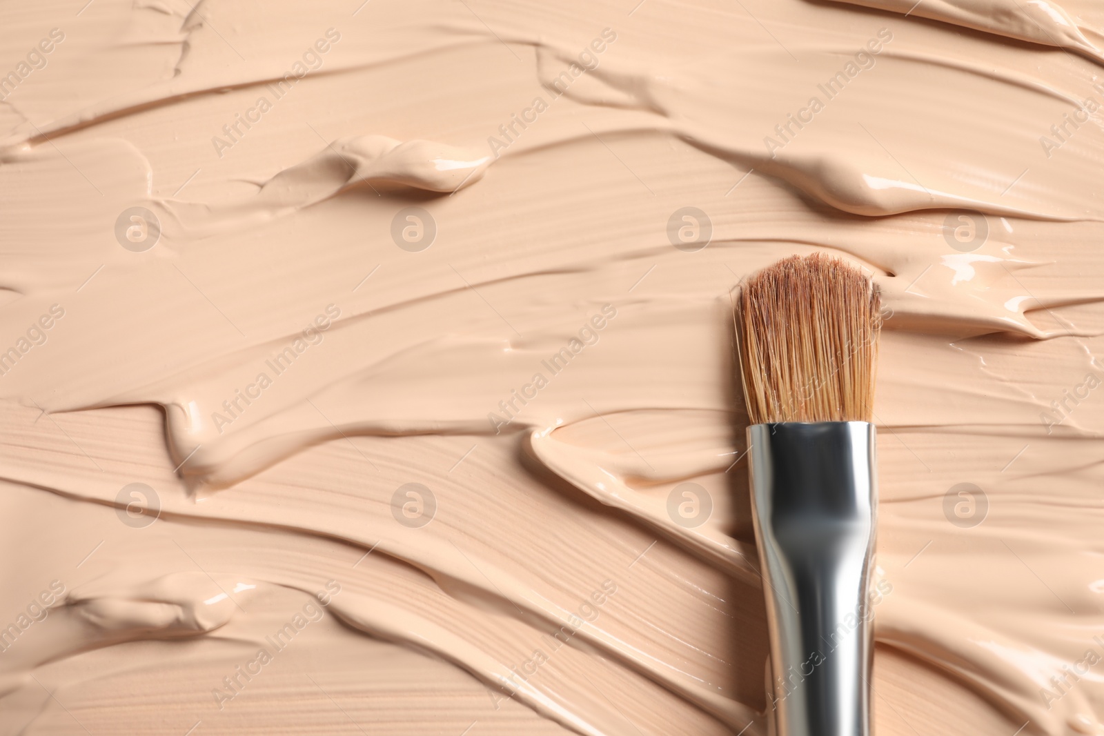 Photo of Skin foundation and makeup brush as background, closeup