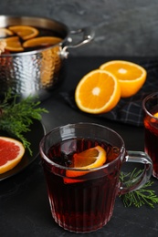 Photo of Tasty mulled wine and fresh ingredients on black table