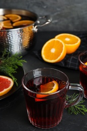 Tasty mulled wine and fresh ingredients on black table