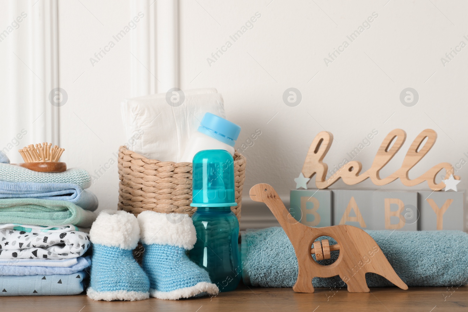 Photo of Baby clothes, toy and accessories on wooden table