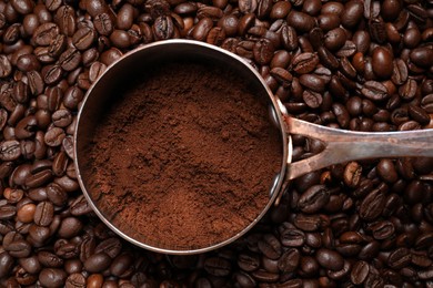 Photo of Pot with ground coffee on roasted beans, top view