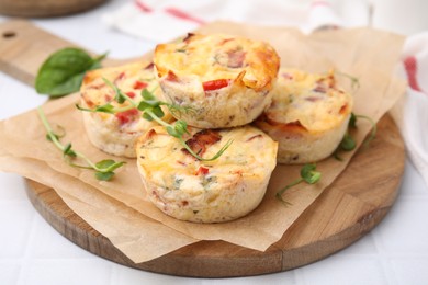 Delicious egg muffins with cheese and bacon on white tiled table, closeup