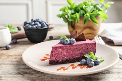 Photo of Plate with piece of tasty blueberry cake on wooden table