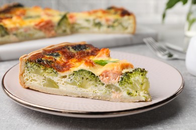 Photo of Piece of delicious homemade quiche with salmon and broccoli on light grey table, closeup