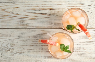 Photo of Glasses of grapefruit cocktails on wooden table, flat lay. Space for text