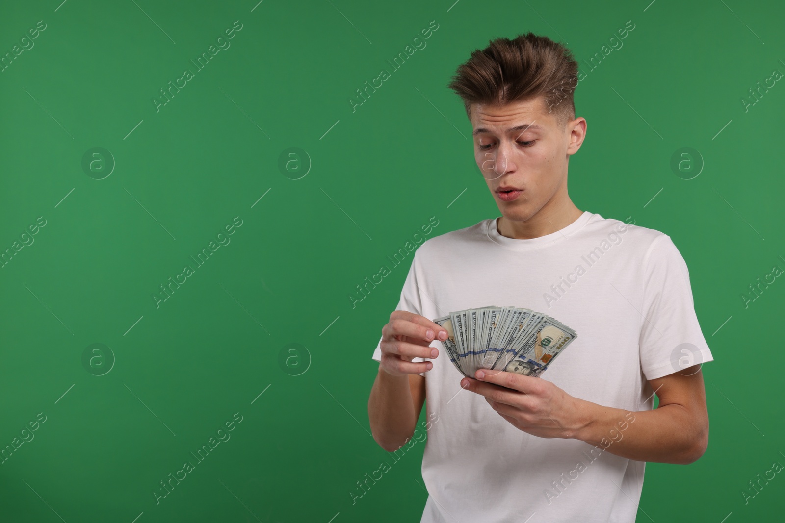 Photo of Handsome man with dollar banknotes on green background. Space for text