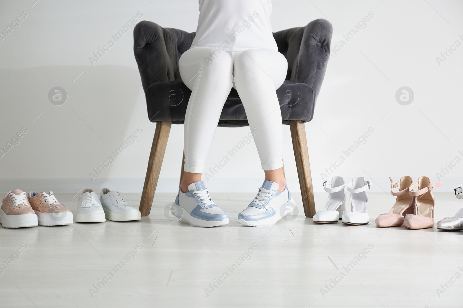 Photo of Young woman choosing shoes while sitting in armchair, closeup