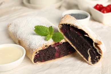 Delicious strudel with cherries and poppy seeds on parchment, closeup