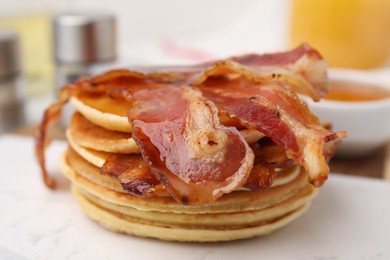 Delicious pancakes with bacon and honey on table, closeup